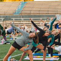 students doing yoga poses on the football field